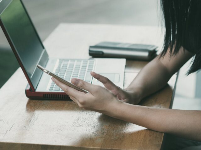 woman sitting on chair beside table while using phone