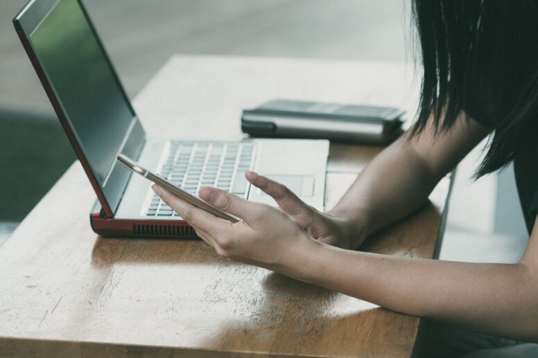 woman sitting on chair beside table while using phone